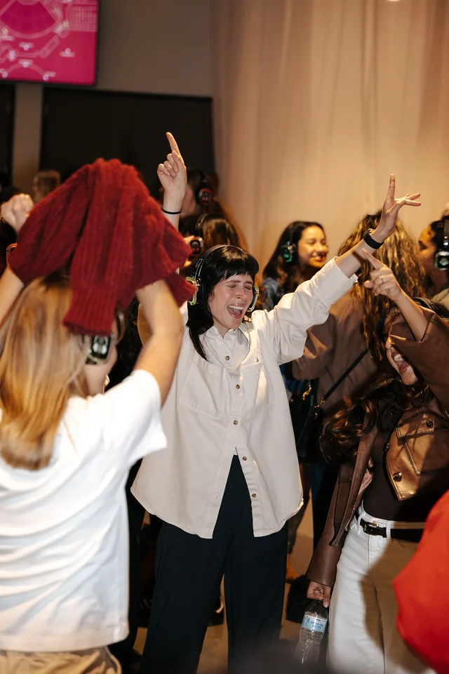 A guest with her arms up, singing along on the dance floor