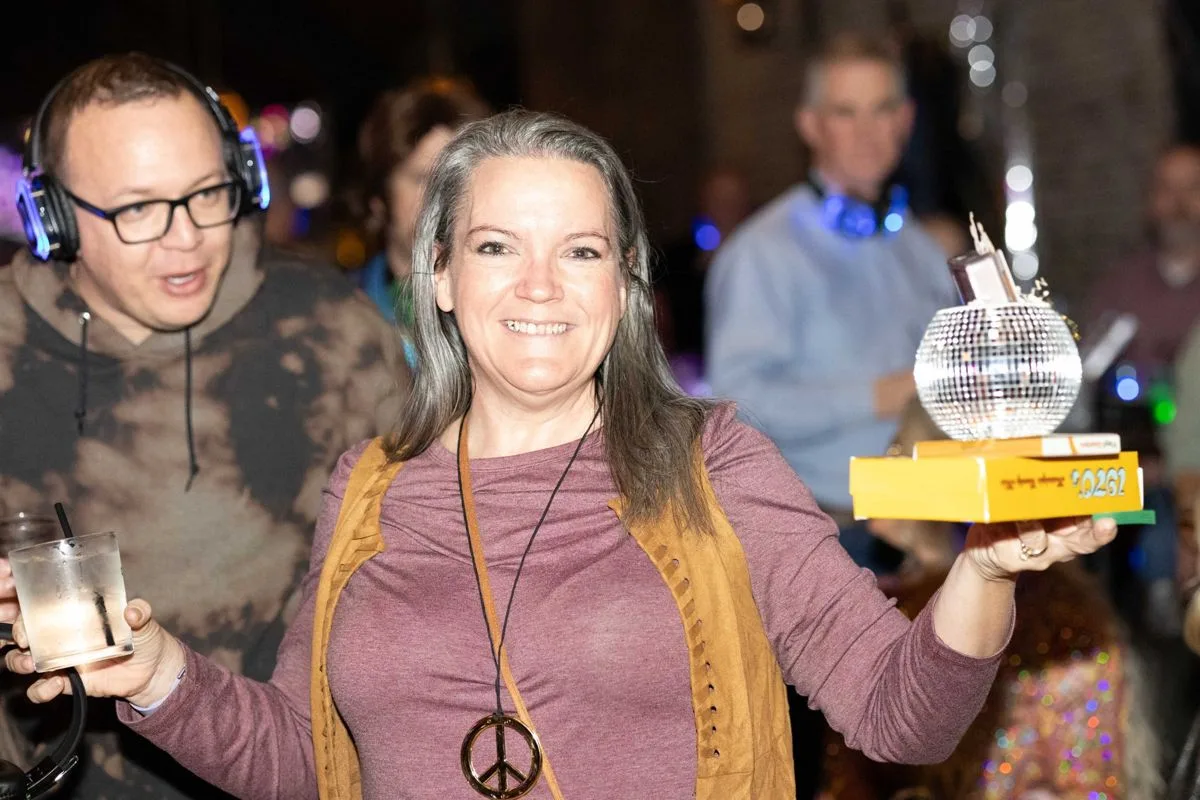 A guest holding up the awards trophy, headphones on