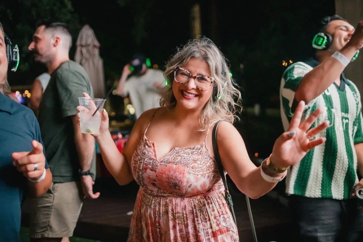 A guest laughing on the patio, drink in hand, headphones on