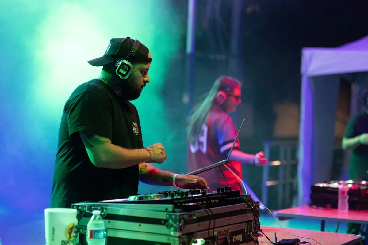 A DJ and vocalist trading energy on stage, teal haze