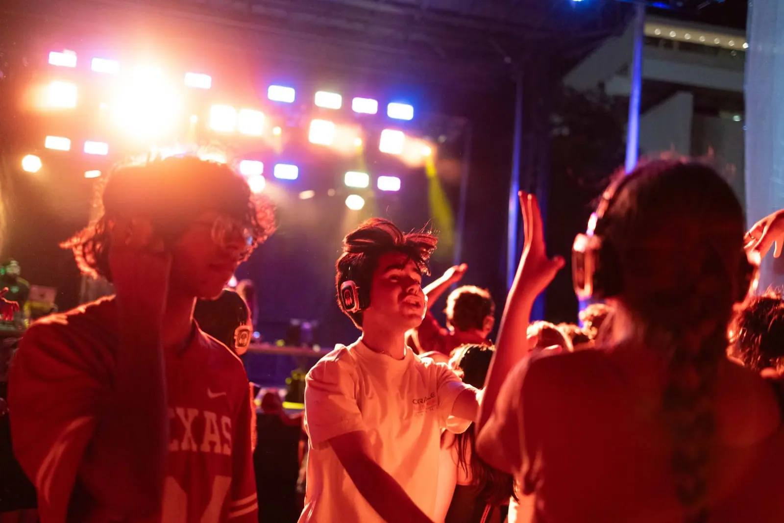 Dancers in Texas shirts, hands up under the stage lights