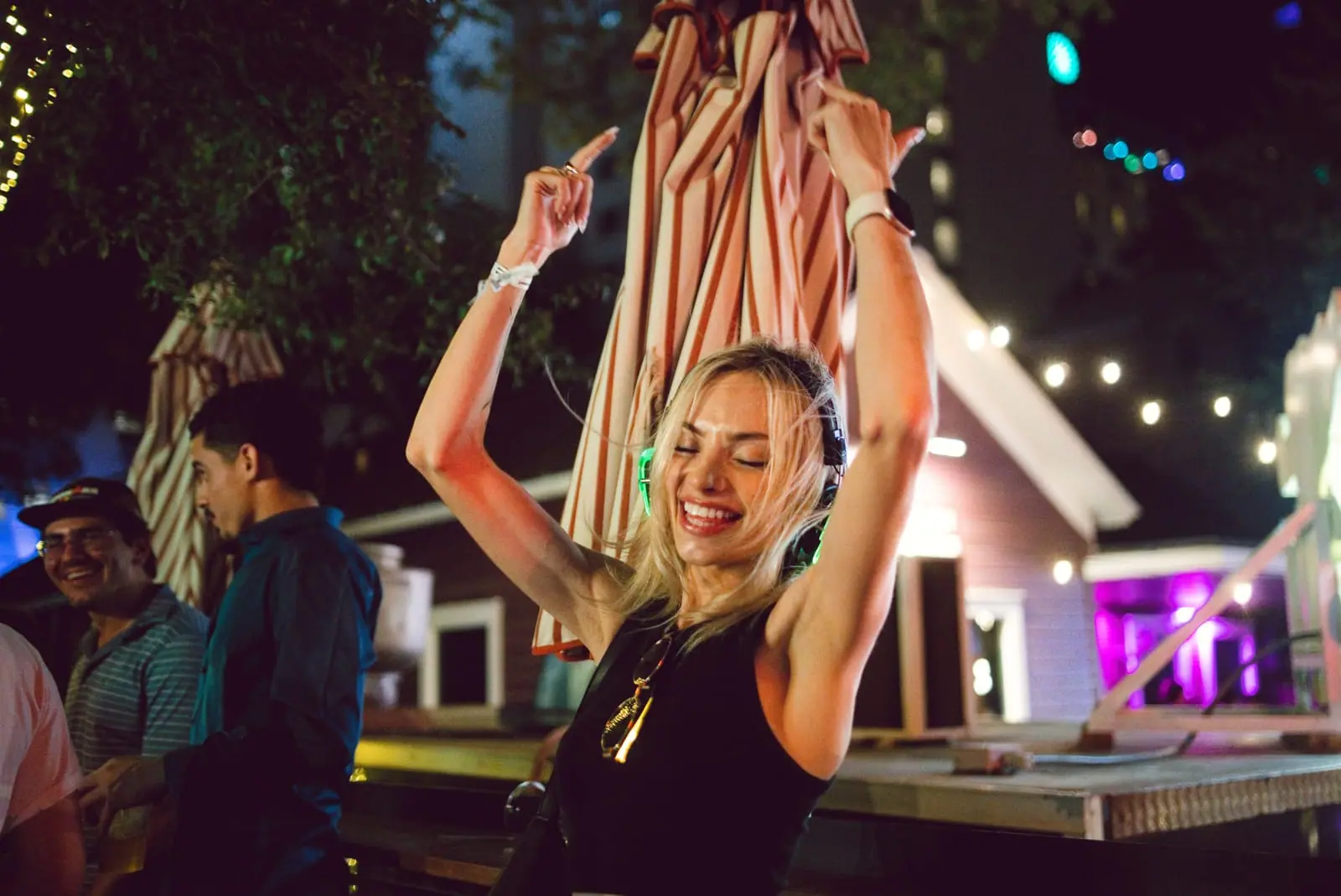 Arms up under the string lights — backyard-bar energy