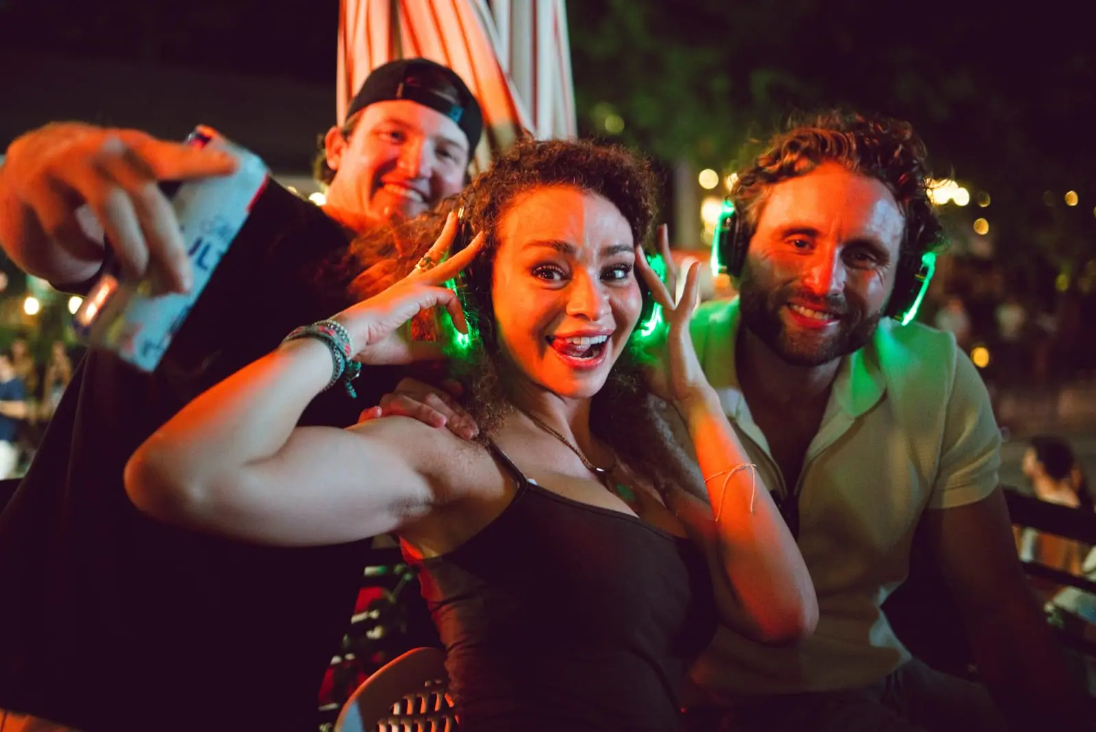 Three friends hamming it up for the camera, green headphones glowing