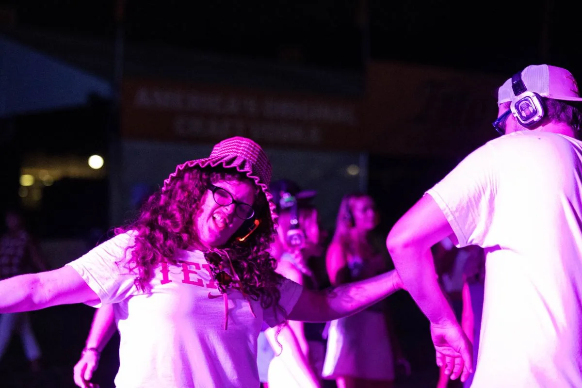 A dancer in a bucket hat mid-move, pink stage light