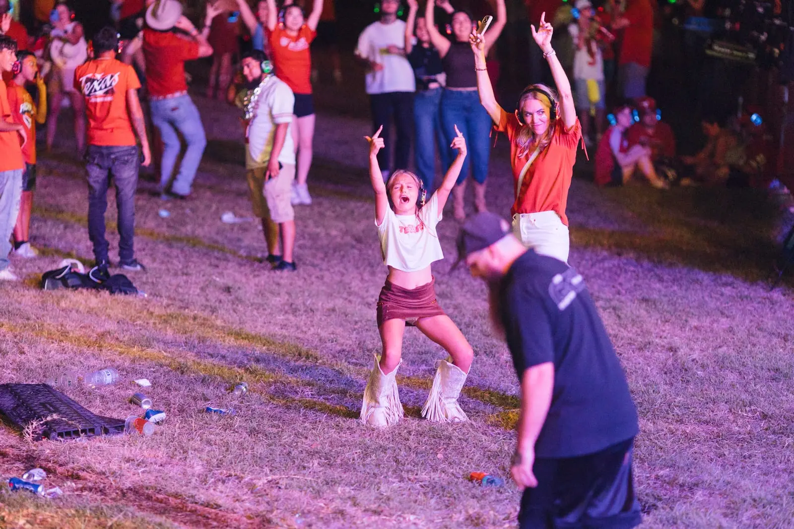 A young dancer throws her arms up on the lawn, purple stage glow behind