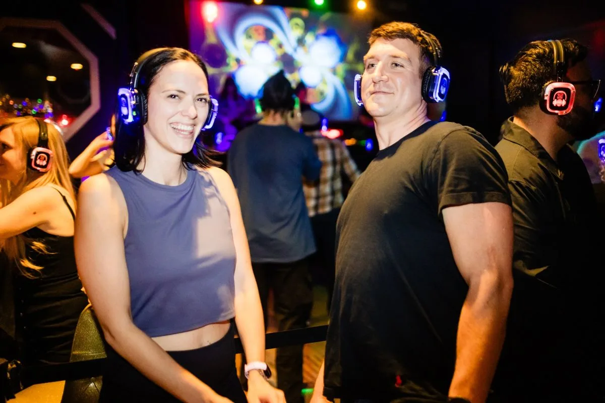 Two guests all smiles on the dance floor, headphones glowing