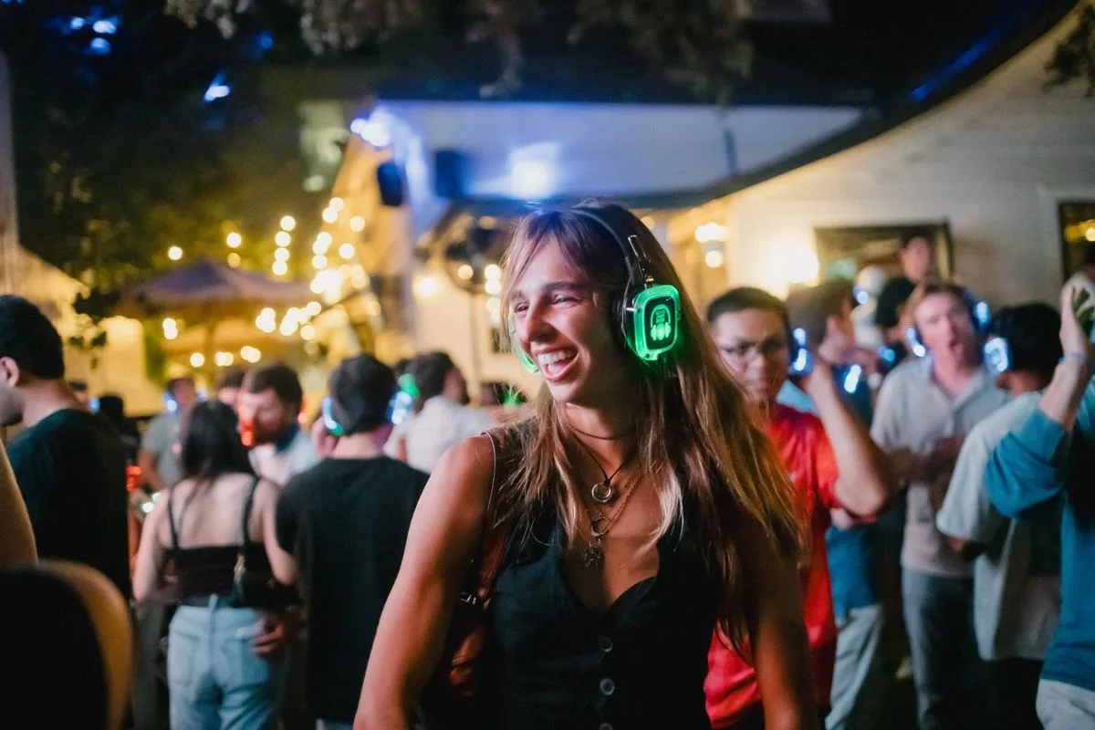 A guest laughing with her whole face, green headphones lit