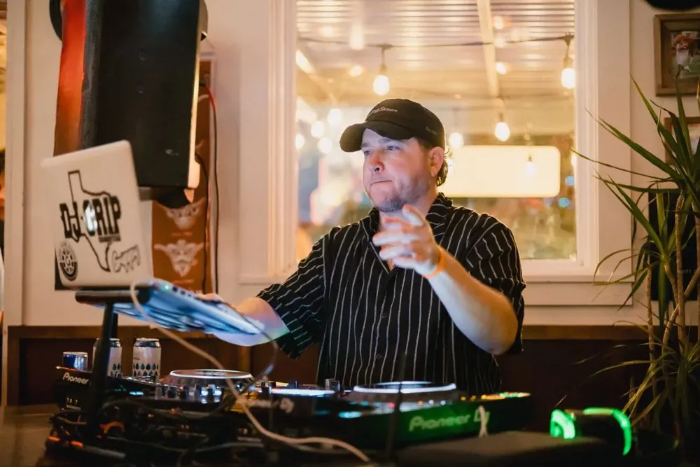 A DJ at the decks pointing at the crowd