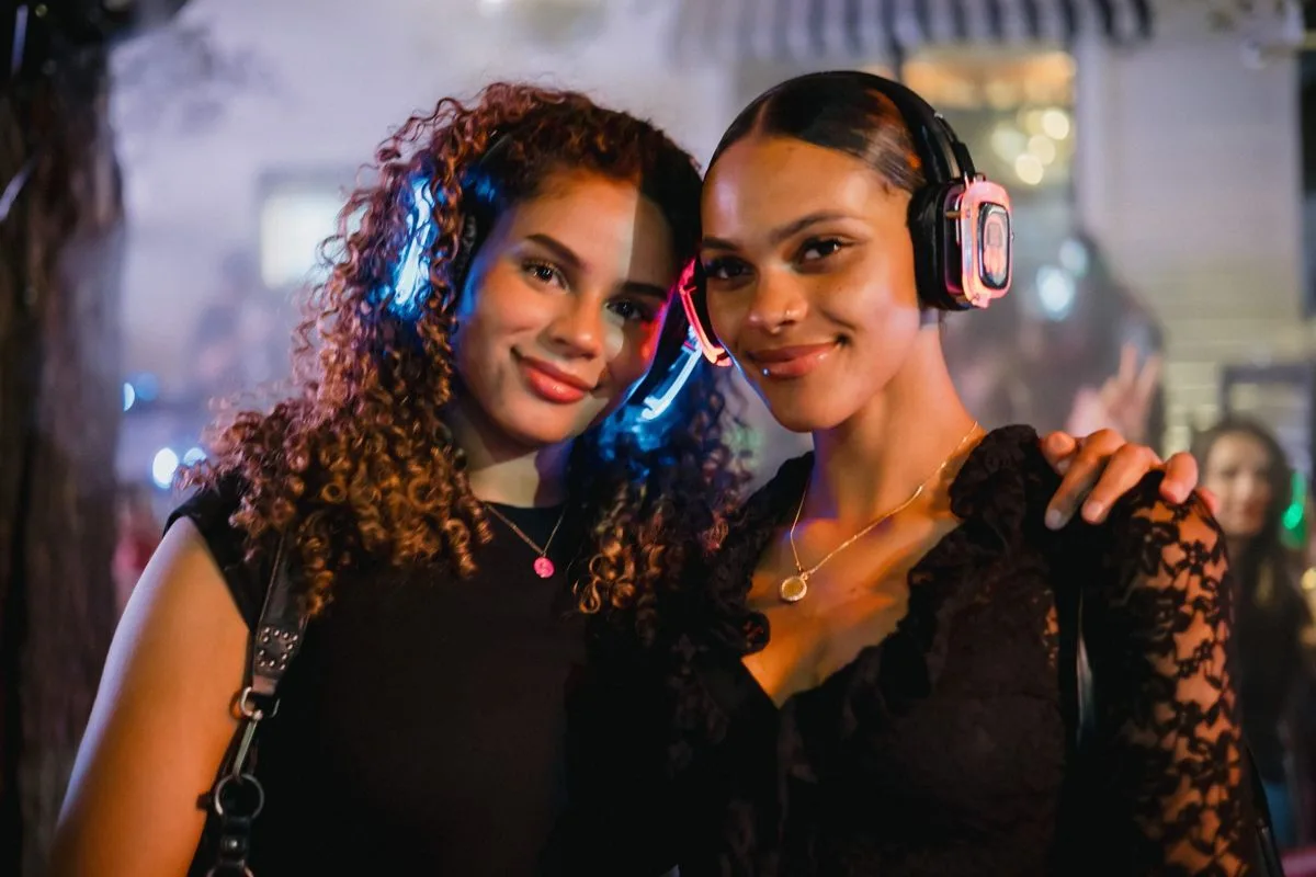 Two friends posing together, glowing headphones on