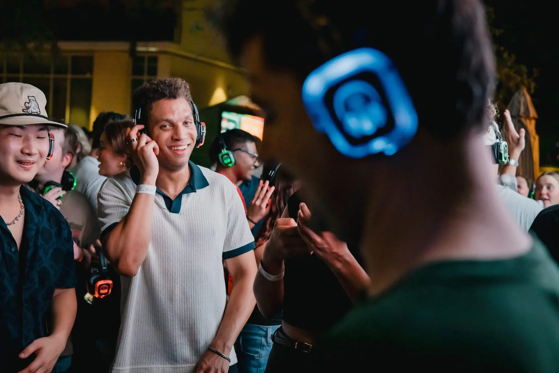 Guests grinning in headphones, a glowing ear cup in the foreground