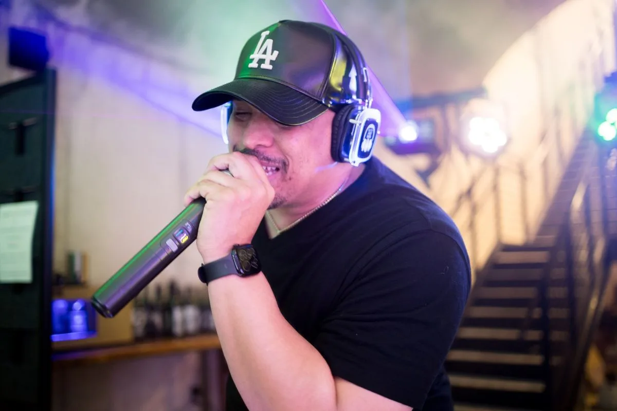 A live MC hyping the room, ball cap and headphones on