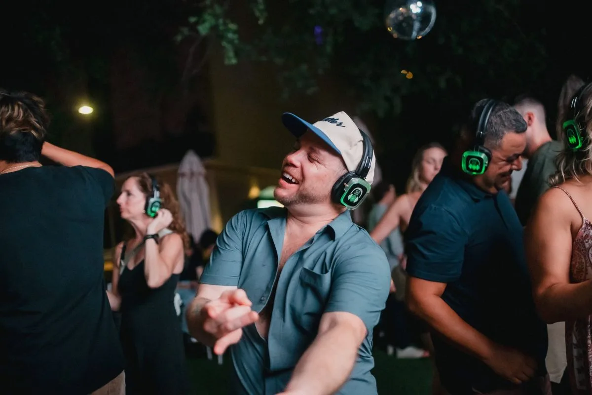 A guest pointing back at the camera, green headphones lit